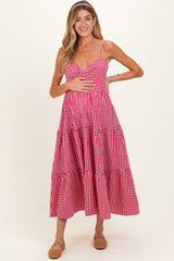 woman wearing a pink gingham maternity dress with tiered skirt and holding her baby bump