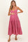 woman wearing a pink gingham maternity dress with tiered skirt and holding her baby bump