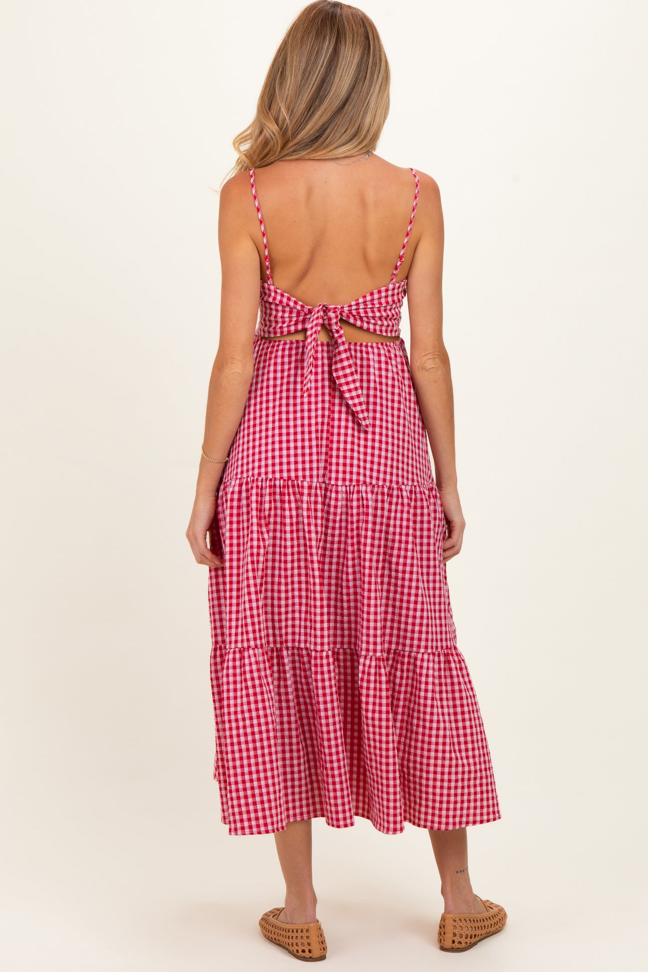 woman wearing a red and white gingham maternity maxi dress with a back tie detail and tiered skirt