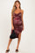 woman wearing a burgundy floral maternity dress with ruching and a thigh-high slit, holding a black bag and showing her baby bump