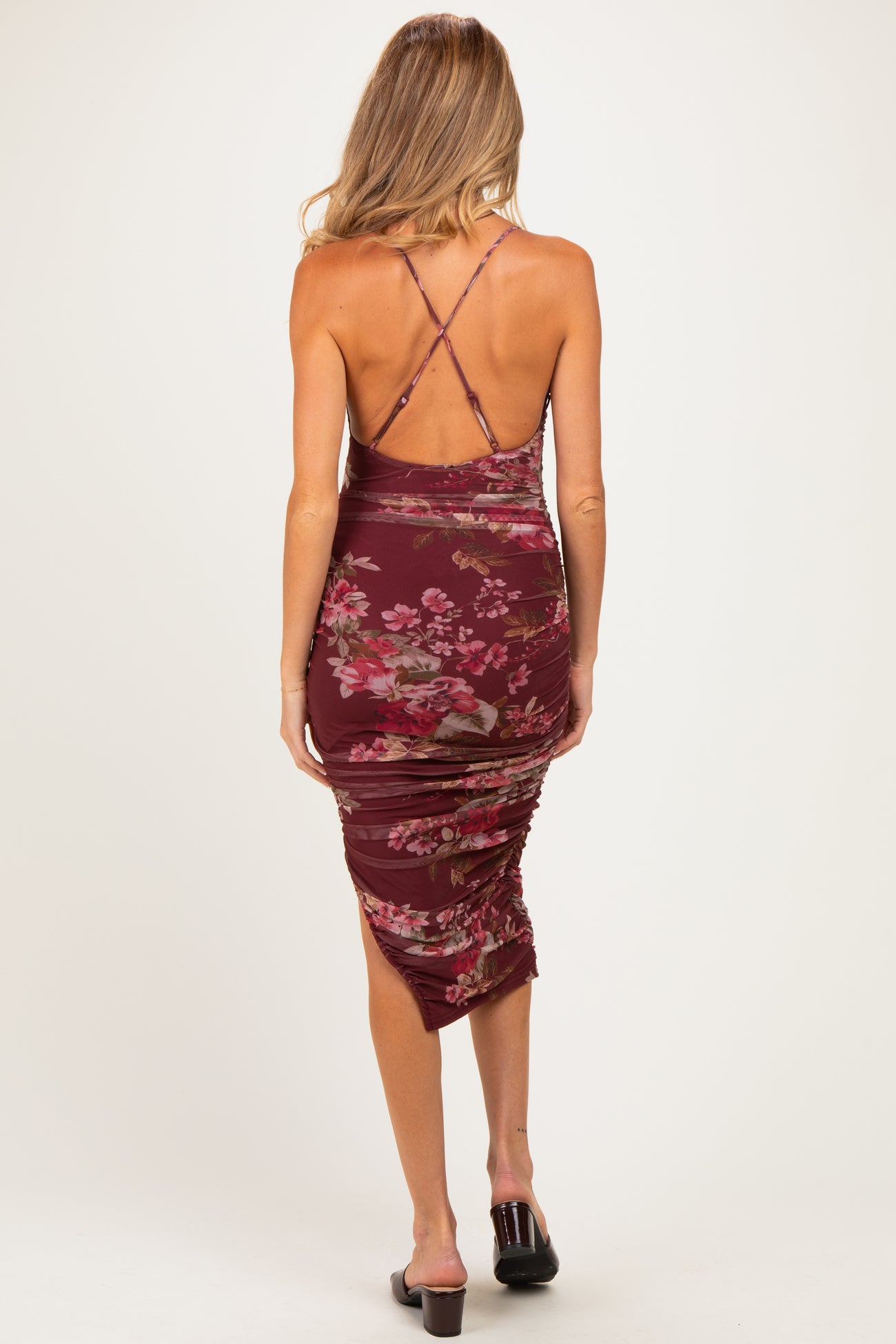 woman wearing a burgundy floral print ruched maternity dress with a crisscross back detail