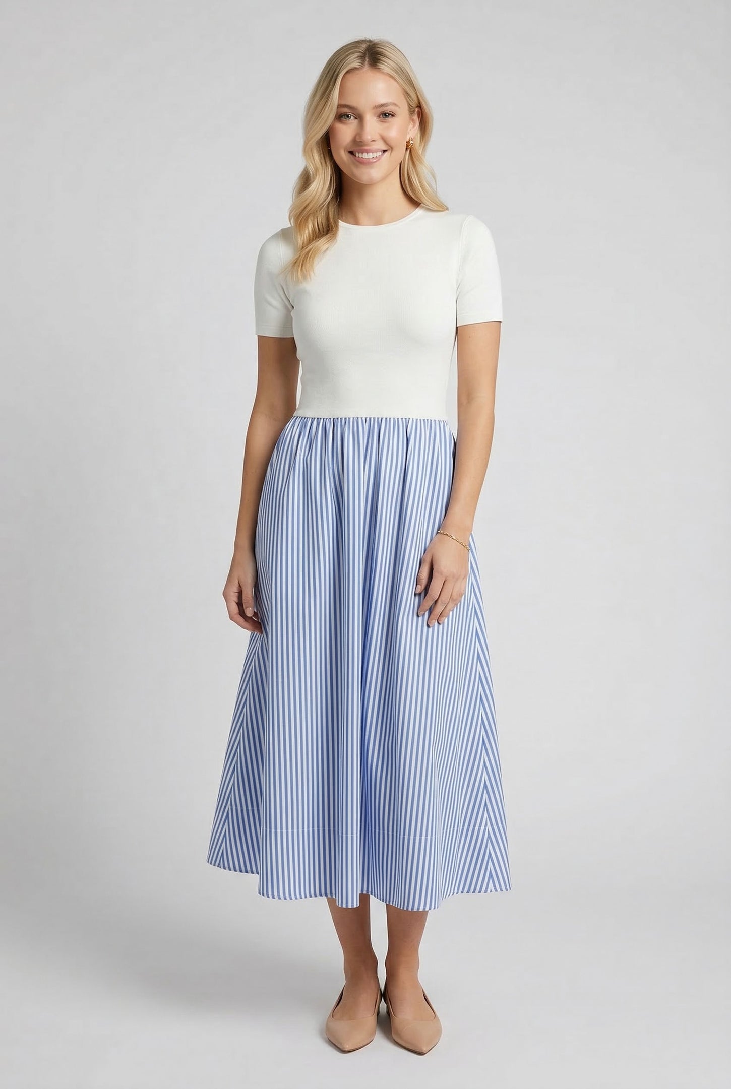 woman wearing a white short sleeve top with a blue and white striped midi skirt and beige heels