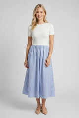 woman wearing a white short sleeve top with a blue and white striped midi skirt and beige heels