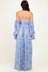 woman wearing a light blue off-the-shoulder maxi dress with long puff sleeves and floral patterns