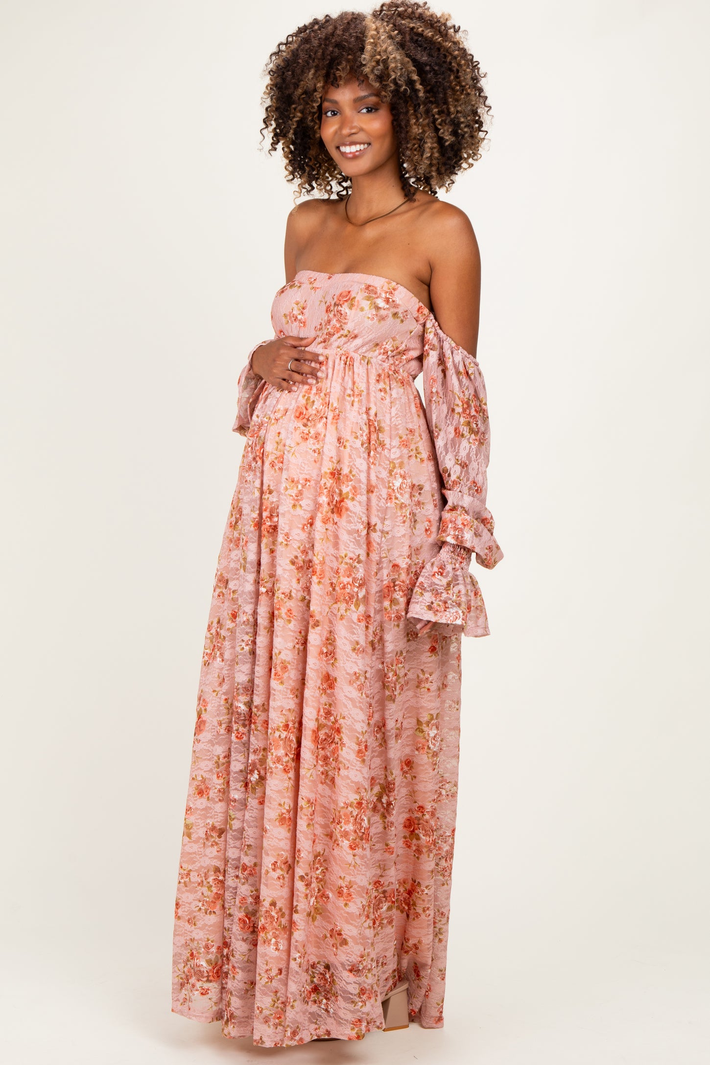 woman wearing a floral strapless pink maternity gown and holding her baby bump