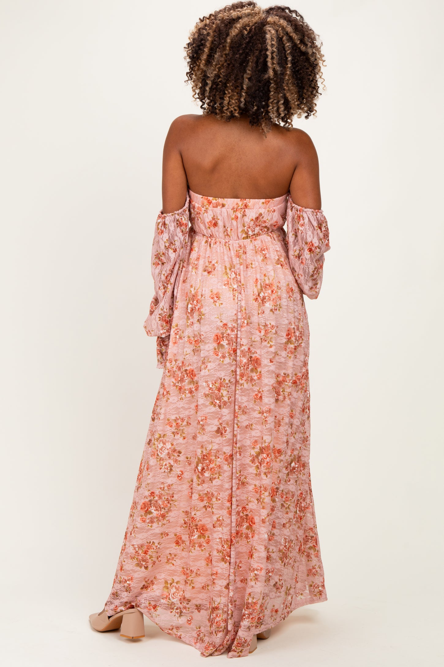 woman wearing a floral off-shoulder maxi maternity dress with long sleeves and a fitted bodice, showing a pregnant belly