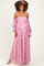 woman wearing a pink floral off-the-shoulder maternity dress with long sleeves and a visible baby bump