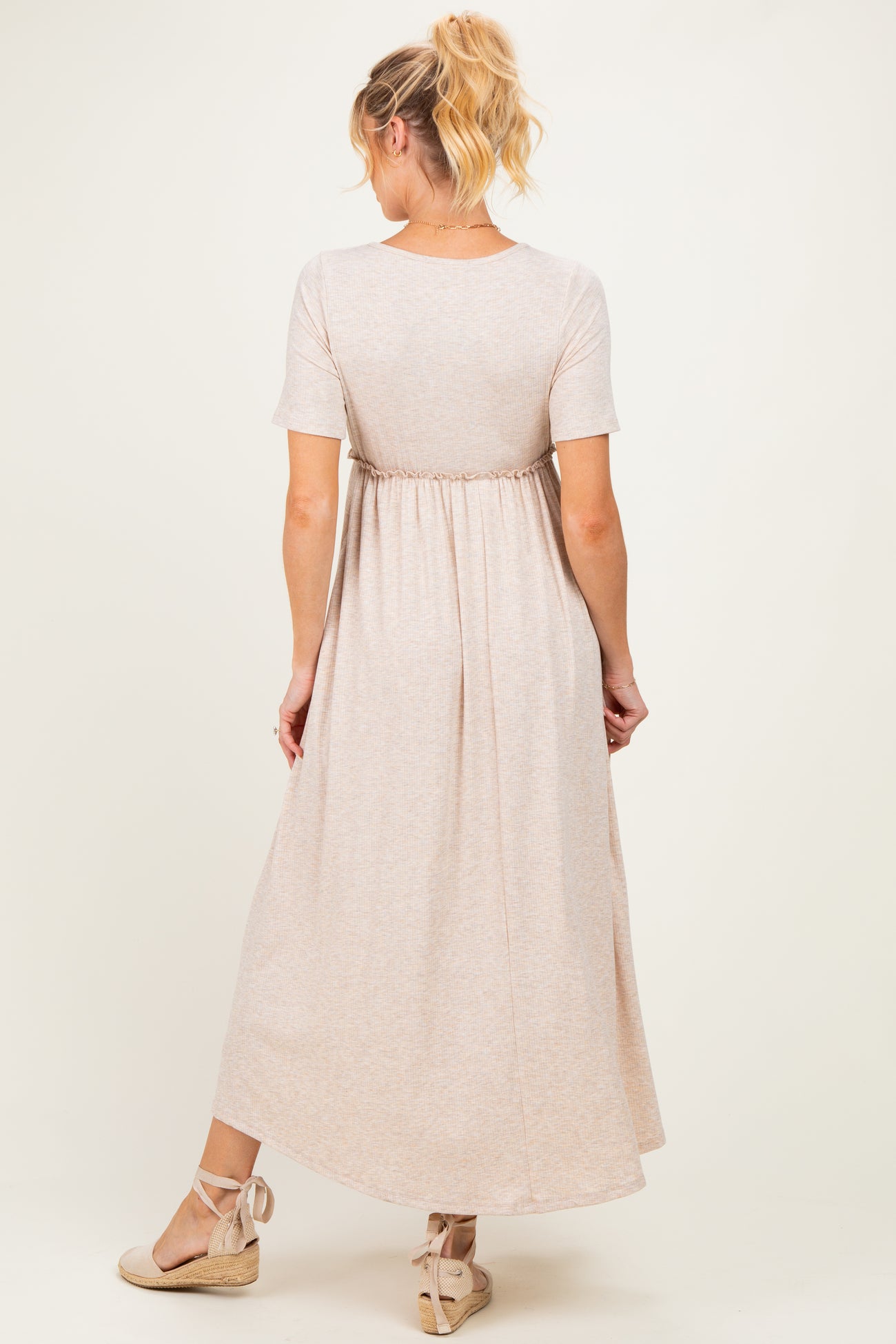 woman wearing a light brown maternity maxi dress with short sleeves and a gathered waist, viewed from the back