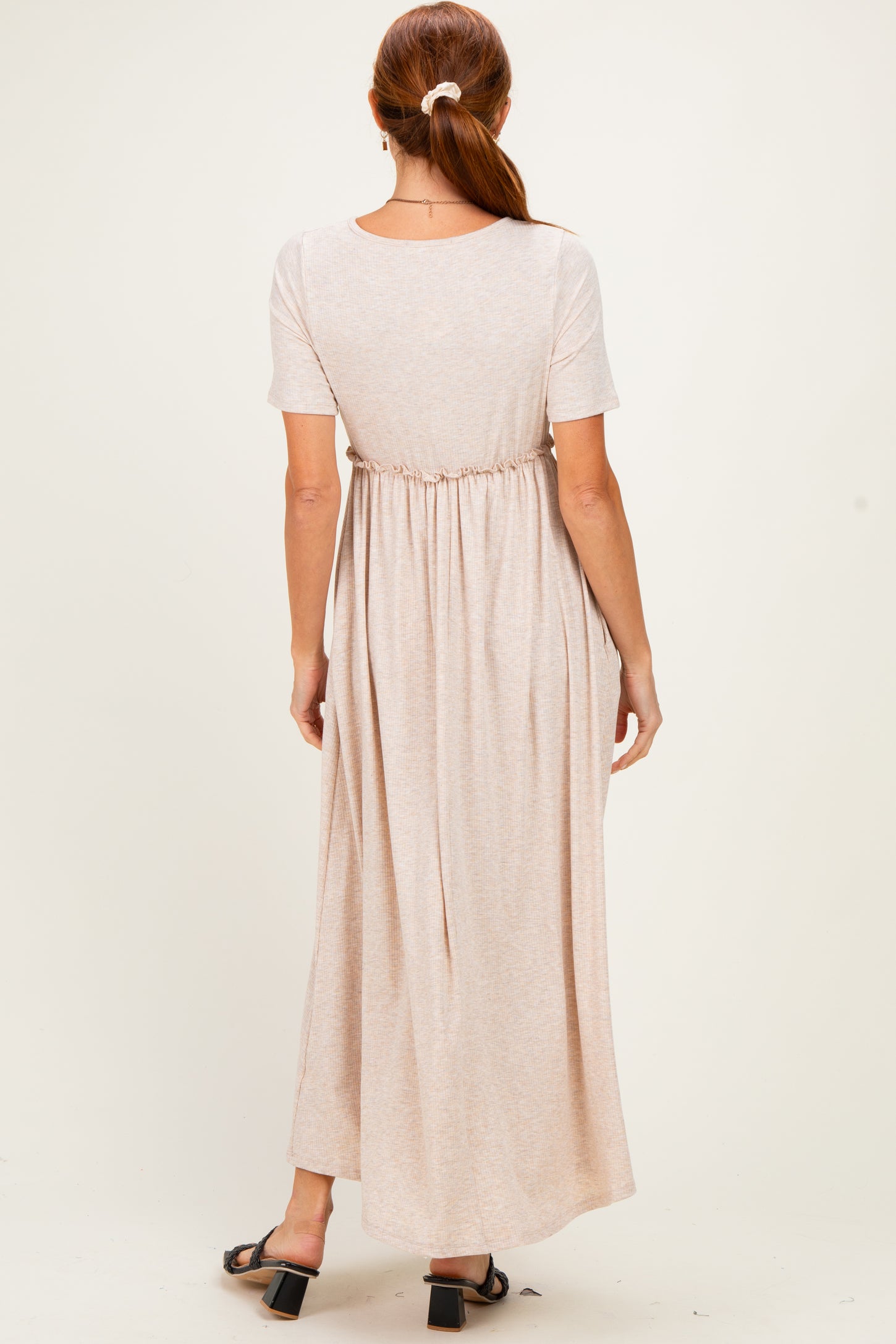 woman wearing a light beige maxi dress with short sleeves and cinched waist, viewed from the back