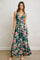 woman wearing a green floral maxi dress with a tie front and spaghetti straps, standing on a neutral background