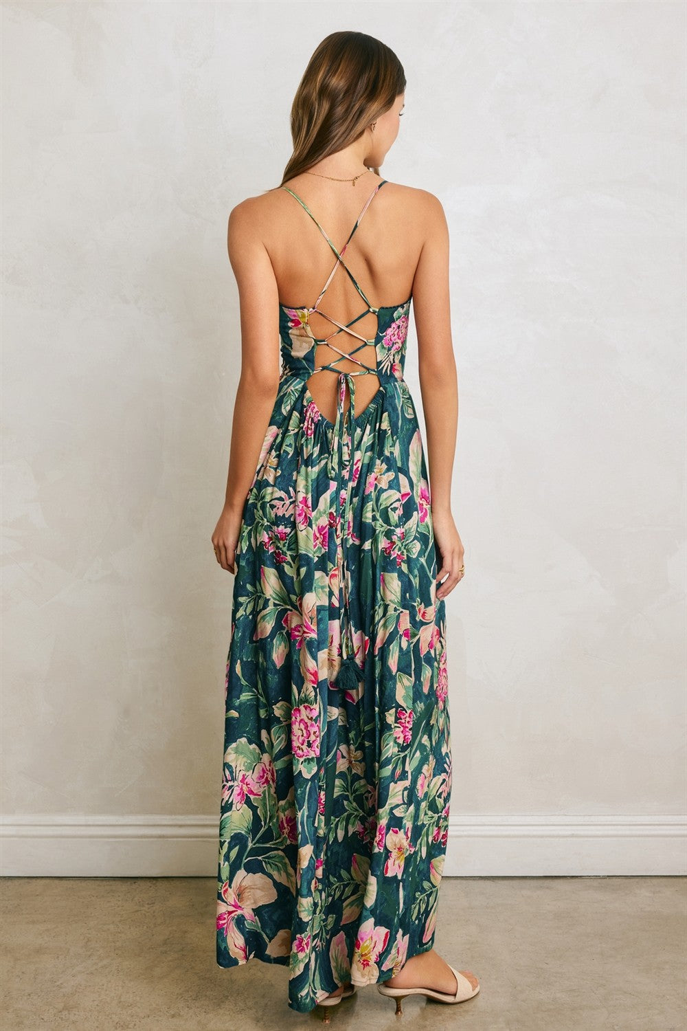 woman wearing a floral maxi dress with a crisscross back detail and a flowy skirt