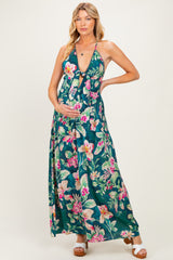 woman wearing a green floral maternity maxi dress and holding her baby bump