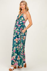 woman wearing a green floral maternity maxi dress with a deep v-neck and side pockets, showing her baby bump