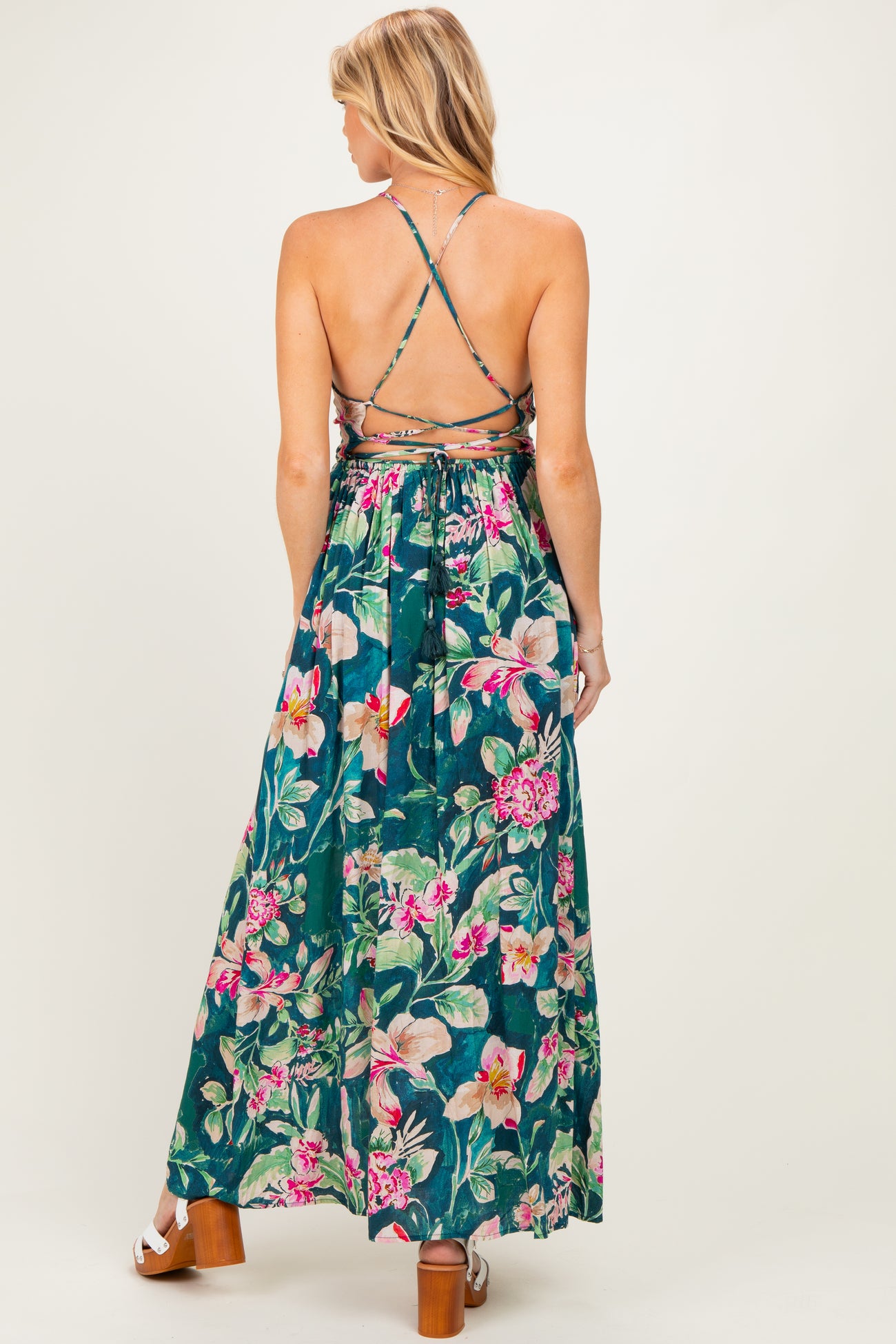 woman wearing a floral print maternity maxi dress with a crisscross back and flowing skirt
