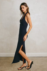 woman wearing a navy blue ribbed maxi dress with a high slit and deep v-neckline, styled with black heeled sandals