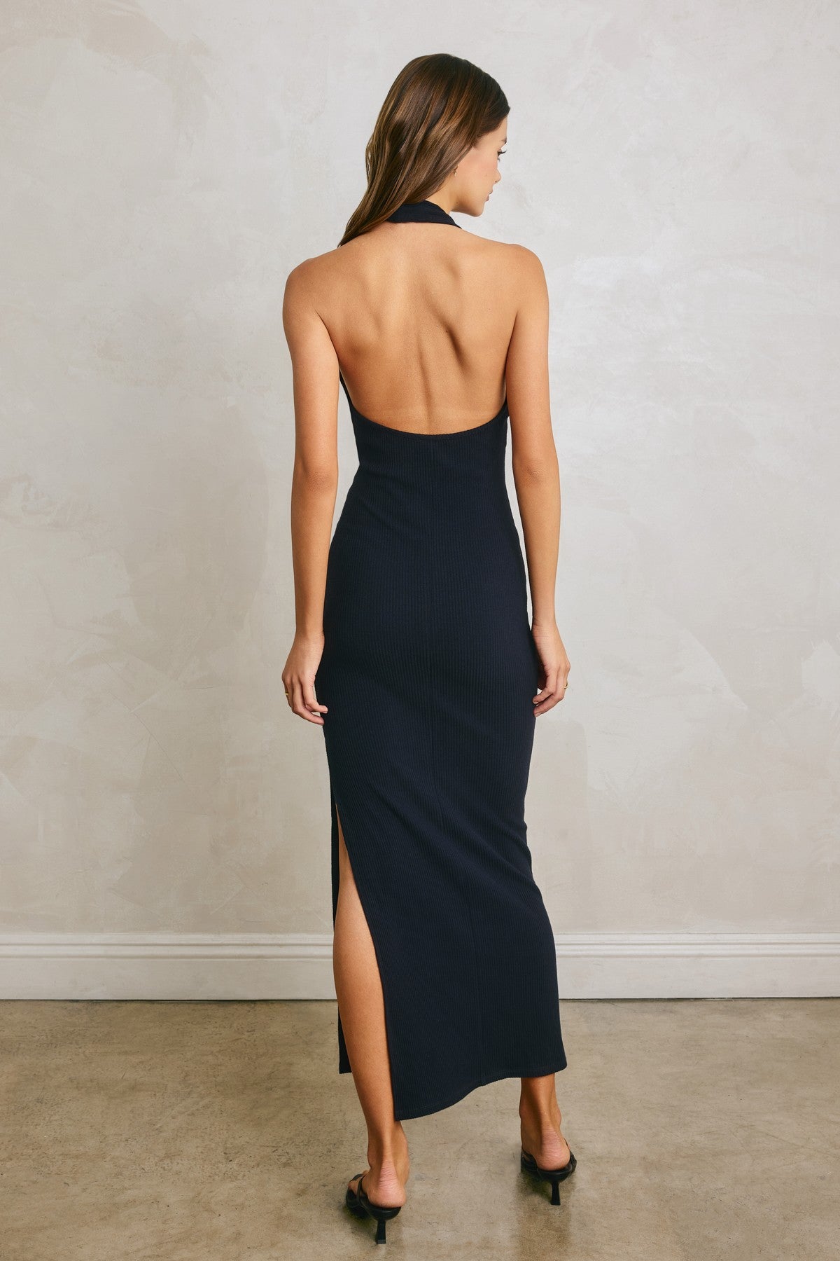 woman wearing a navy ribbed halter neck maxi dress with a low back and side slit