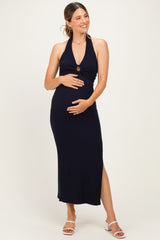 woman wearing a navy blue halter neck maternity dress with a side slit and holding her baby bump