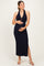 woman wearing a navy blue halter neck maternity dress with a side slit and holding her baby bump