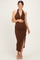 woman wearing a brown halter neck maternity dress with a side slit and holding her baby bump