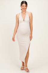 woman wearing a beige halter neck maternity dress with a side slit and a baby bump visible