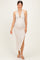 woman wearing a beige halter neck maternity dress with a side slit and a baby bump visible