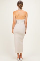 woman wearing a beige ribbed halter neck maternity dress, showing off her baby bump from the back