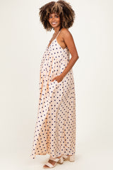 woman wearing a blush pink maternity dress with navy polka dots and pockets, showing baby bump