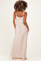 woman wearing a peach polka dot maternity maxi dress, showing a relaxed fit and adjustable straps from the back