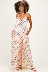woman wearing a peach polka dot maternity maxi dress with adjustable straps and side pockets, showcasing her baby bump
