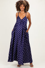 woman wearing a navy blue maternity maxi dress with white polka dots and pockets, showing off her baby bump