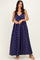 woman wearing a navy blue polka dot maxi dress with a tie detail at the bust and a flowing skirt