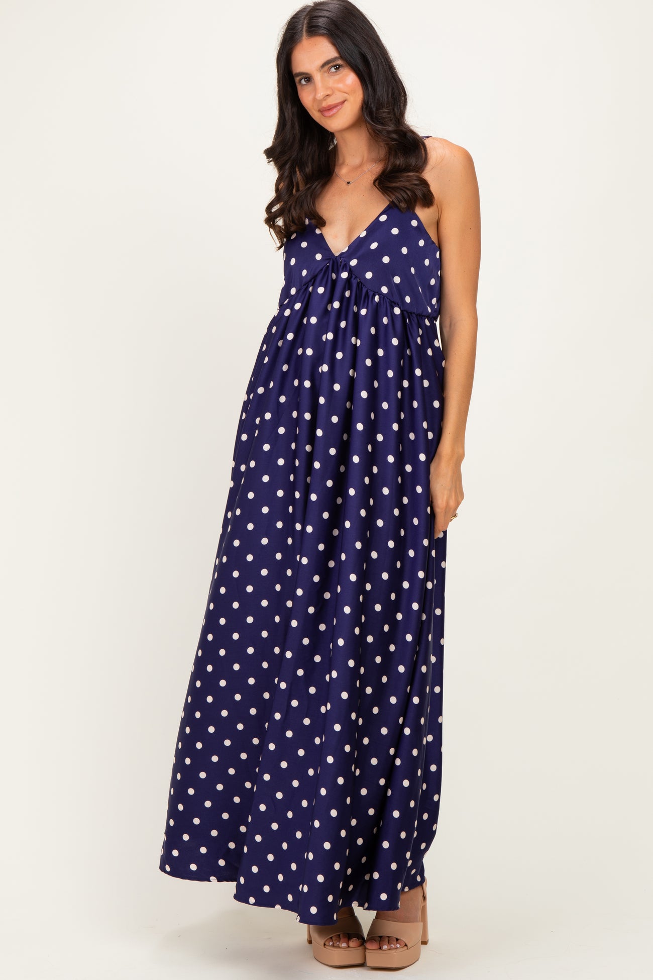 woman wearing a navy blue maxi dress with white polka dots and a tie front detail