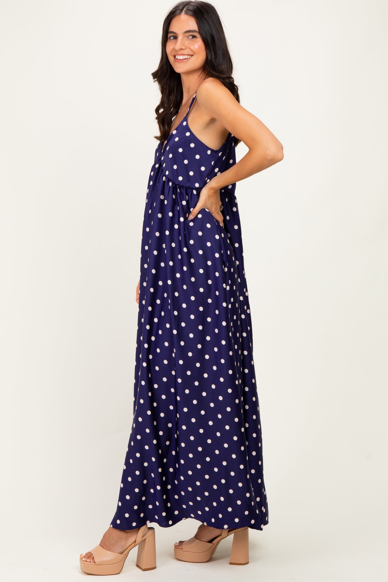 woman wearing a navy blue polka dot maxi dress with pockets and a relaxed fit, posing sideways