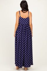 woman wearing a navy blue polka dot maxi dress with a flowy skirt and adjustable spaghetti straps from the back