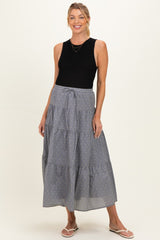 woman wearing a black sleeveless top and a long tiered gray maternity skirt with a tie waist