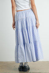woman wearing a light blue tiered maxi skirt with red polka dots and an elastic waistband, seen from the back