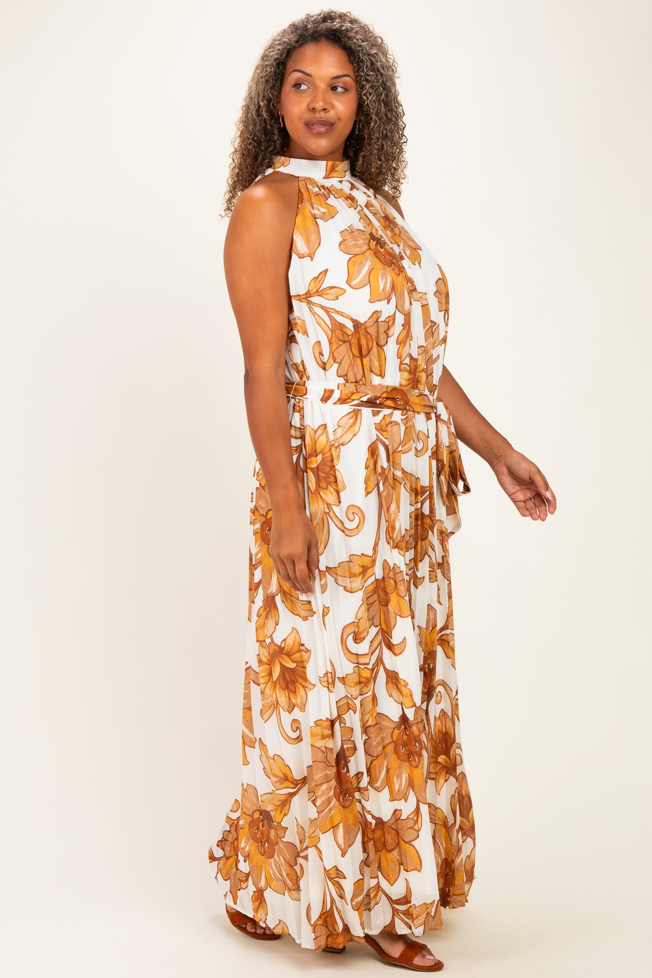 woman wearing a white floral print maxi dress with orange and yellow flowers and a belt, styled for plus size fashion