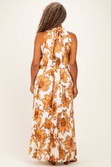 woman wearing a white maxi dress with large orange floral patterns and a halter neck, seen from the back