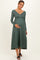 woman wearing a green ribbed maternity dress with long sleeves and button detail, holding her baby bump