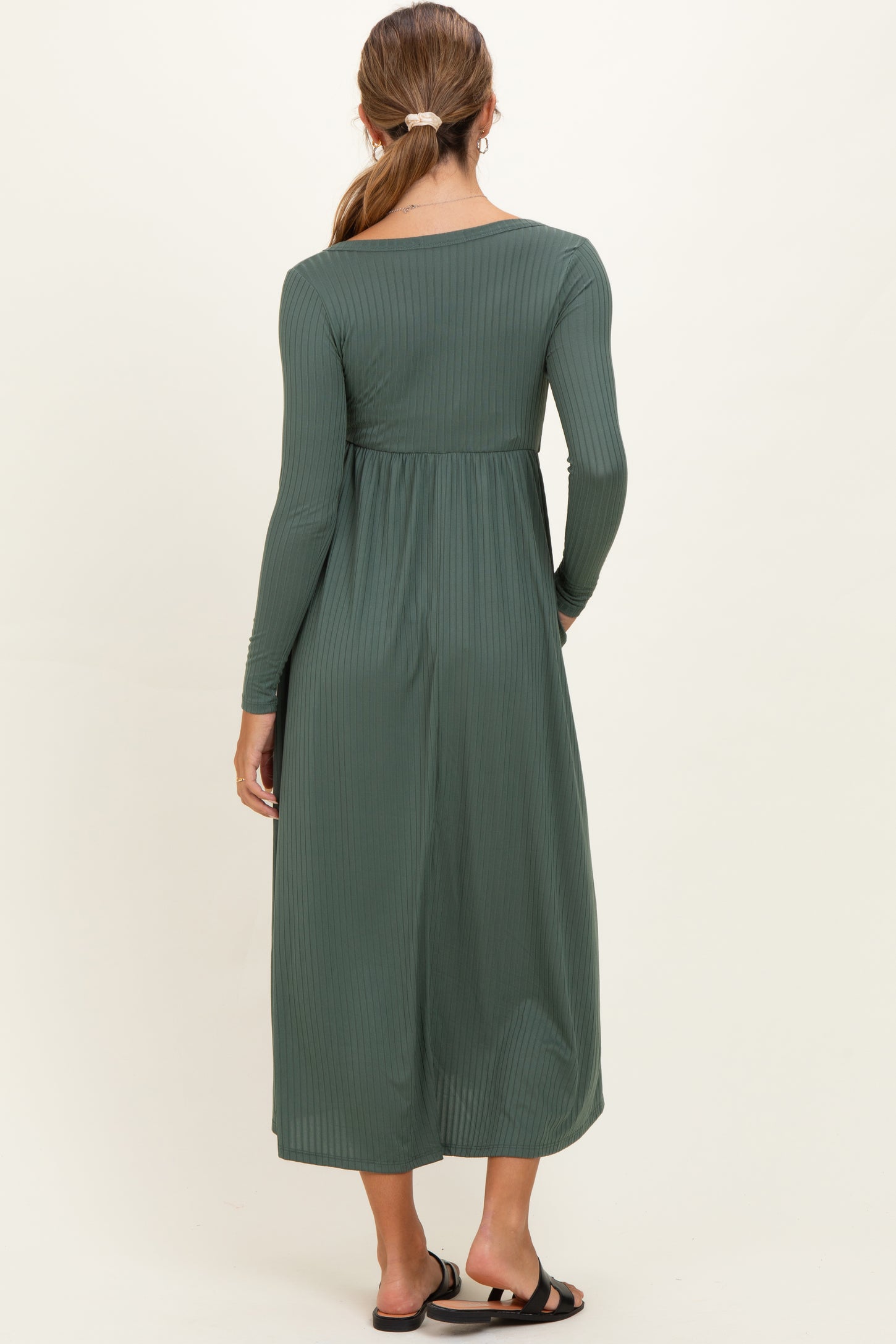 woman wearing a dark green long sleeve maternity dress with a textured ribbed design, shown from the back