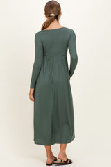 woman wearing a dark green long sleeve maternity dress with a textured ribbed design, shown from the back
