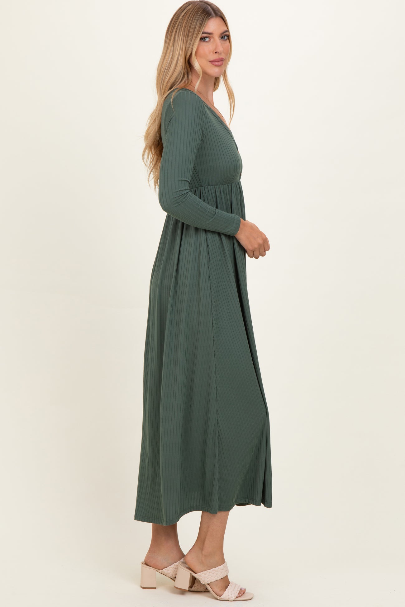 woman wearing a long green ribbed maxi dress with long sleeves and a relaxed fit, standing in profile