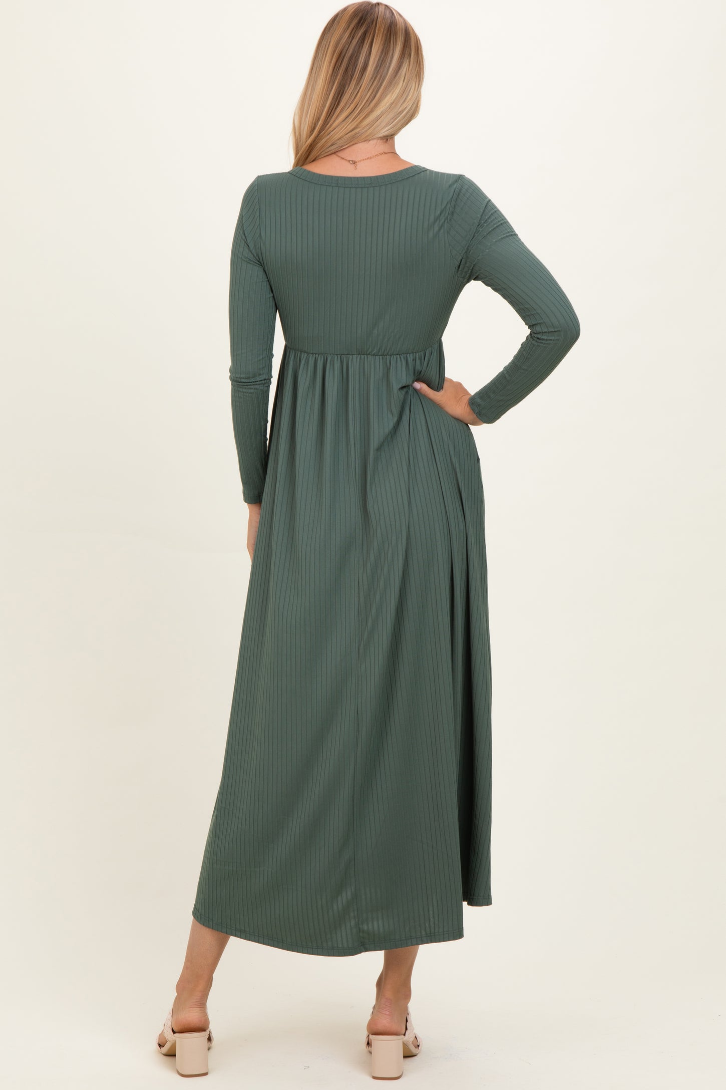 woman wearing a long green ribbed maxi dress with long sleeves and a fitted waist, seen from the back