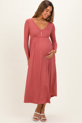 woman wearing a dusty rose long sleeve maternity dress with buttons and gently holding her baby bump