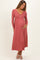 woman wearing a dusty rose long sleeve maternity dress with buttons and gently holding her baby bump