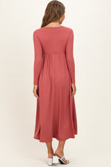 woman wearing a dusty rose long sleeve maternity dress with a flowing skirt and a fitted bodice, viewed from the back