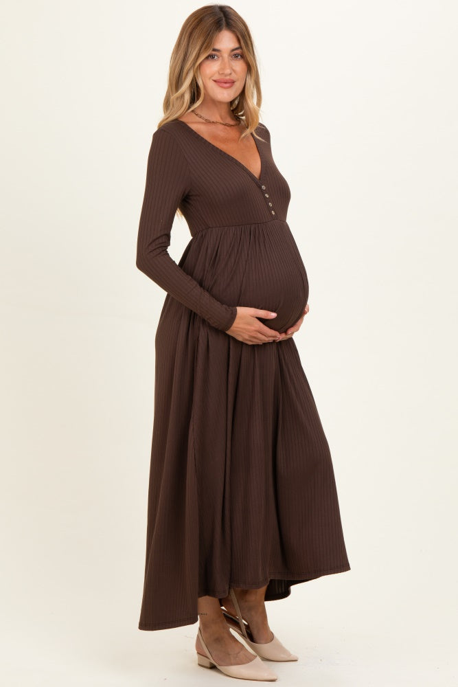 woman wearing a brown ribbed long sleeve maternity dress with a button detail and holding her baby bump