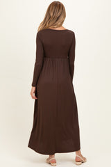 woman wearing a brown long sleeve maternity dress with a fitted waist and flowing skirt, viewed from the back