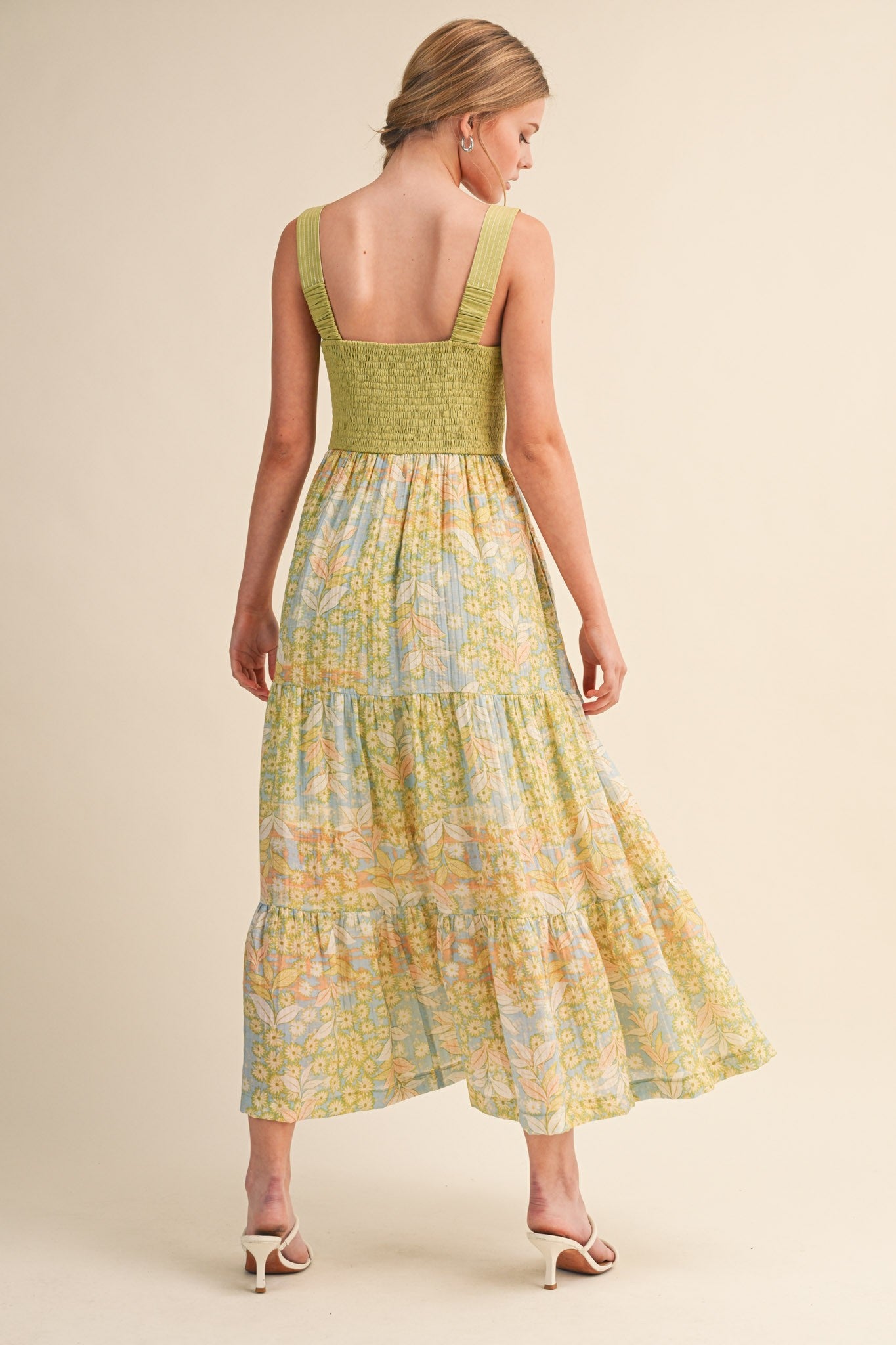 woman wearing a green smocked back maxi dress with floral prints and tiered skirt from the back