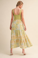 woman wearing a green smocked back maxi dress with floral prints and tiered skirt from the back